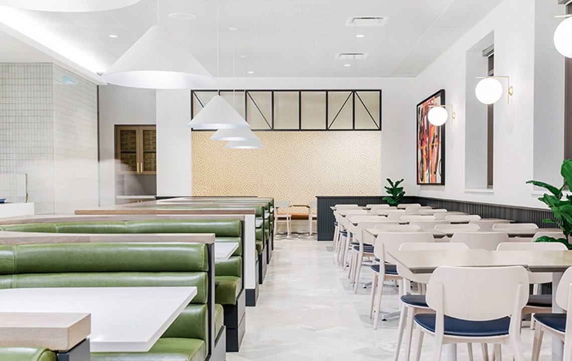 Green dining booths to the left and white chairs and tables to the right
