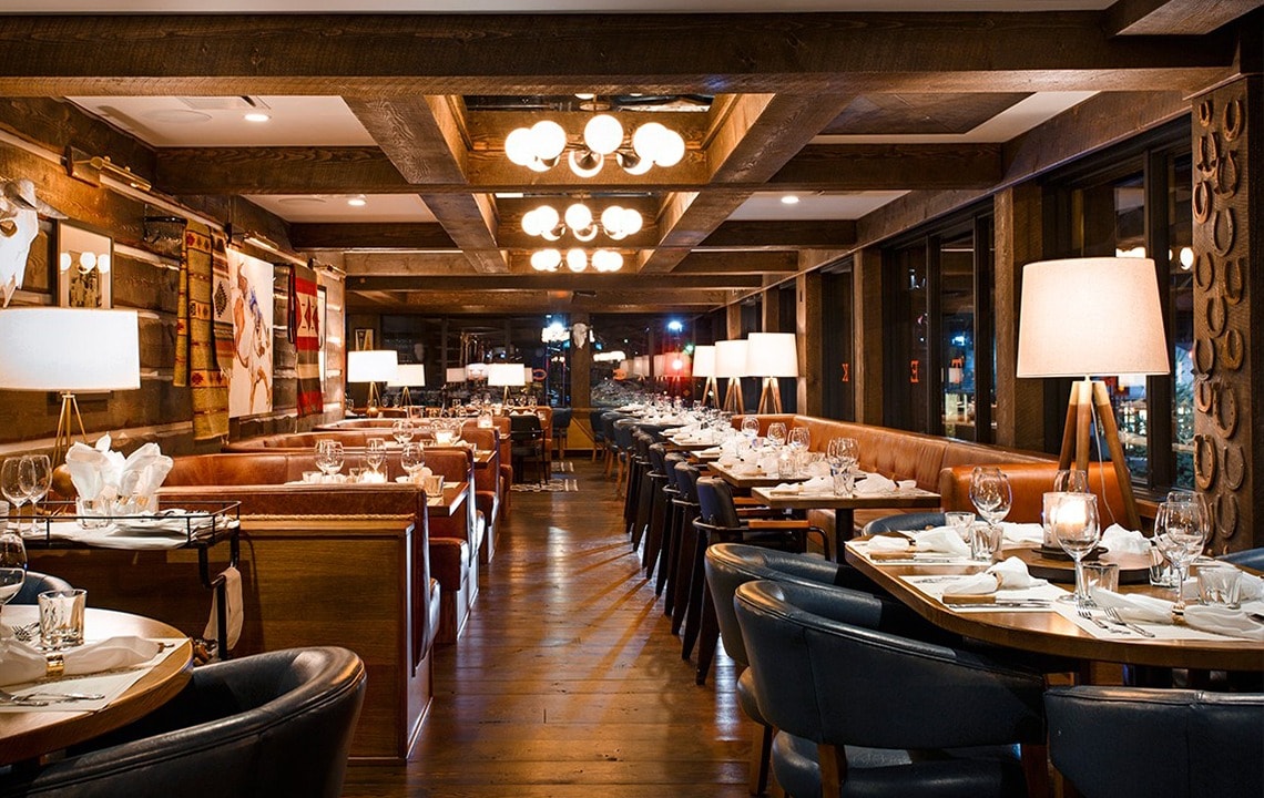 Brown dining booths to the left and blue chairs facing set tables and long seating booth to the right