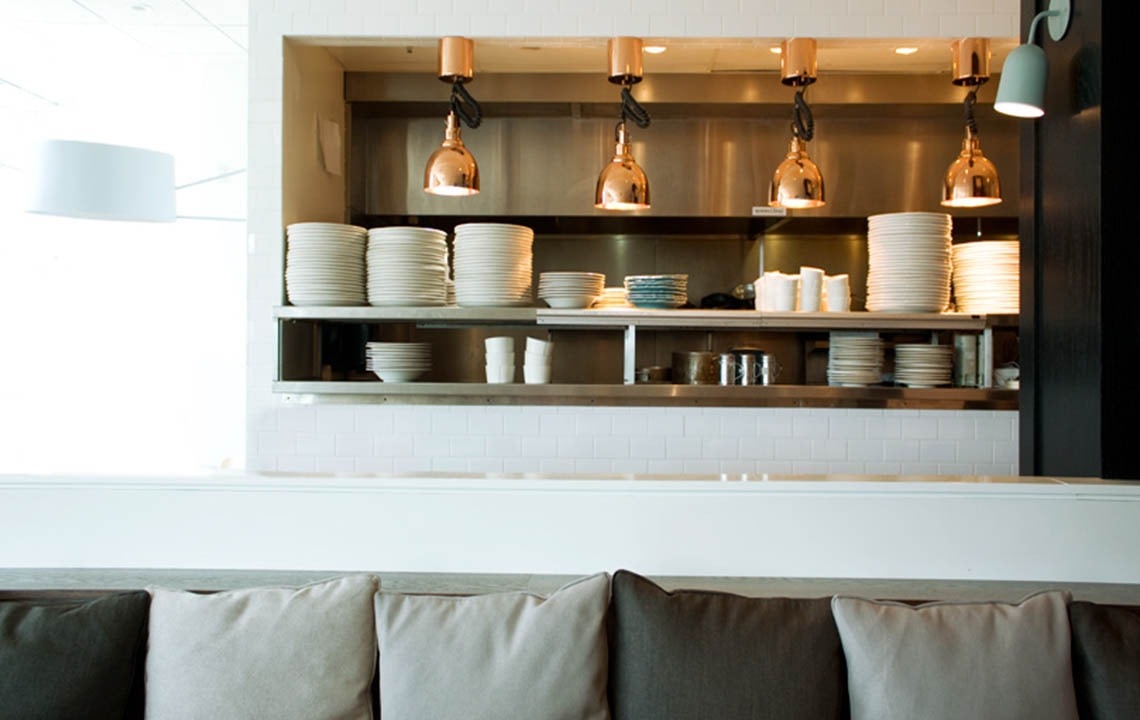 Pillows lined up in foreground with plates stacked on shelves in the background