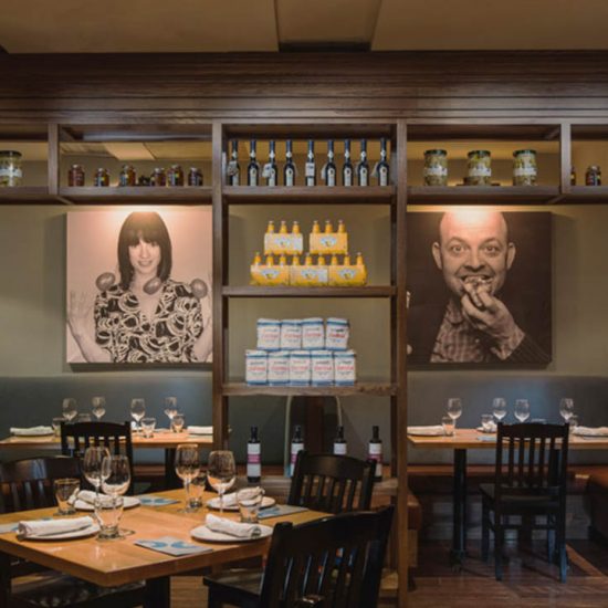 Chairs surrounding set dining tables with large portraits of people eating in the background