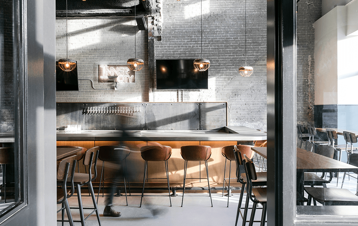 Brown bar chairs facing a bar a concrete bar and distressed grey brick wall