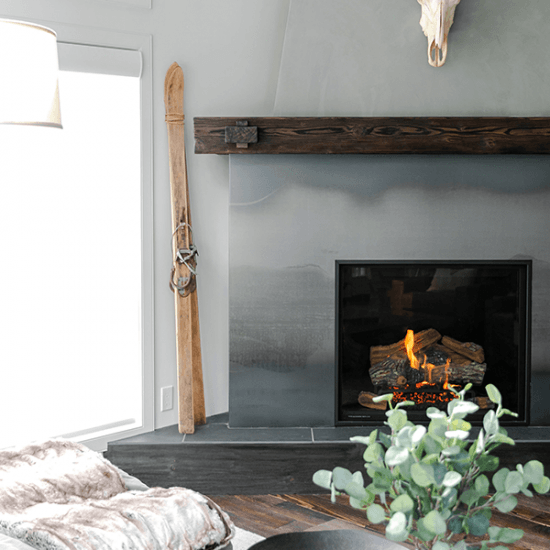 Old wooden skis rest against a wall next to a burning fire place