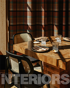 Black and tan chairs surround a wooden table set with cutlery and cups