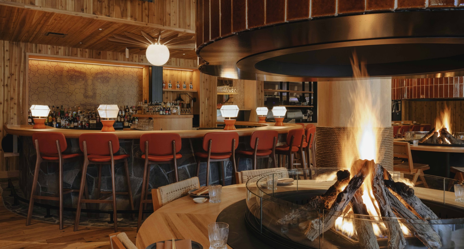 A burning fireplace in the centre of the Hello Sunshine restaurant is surrounded by wicker chairs and set dining cutlery
